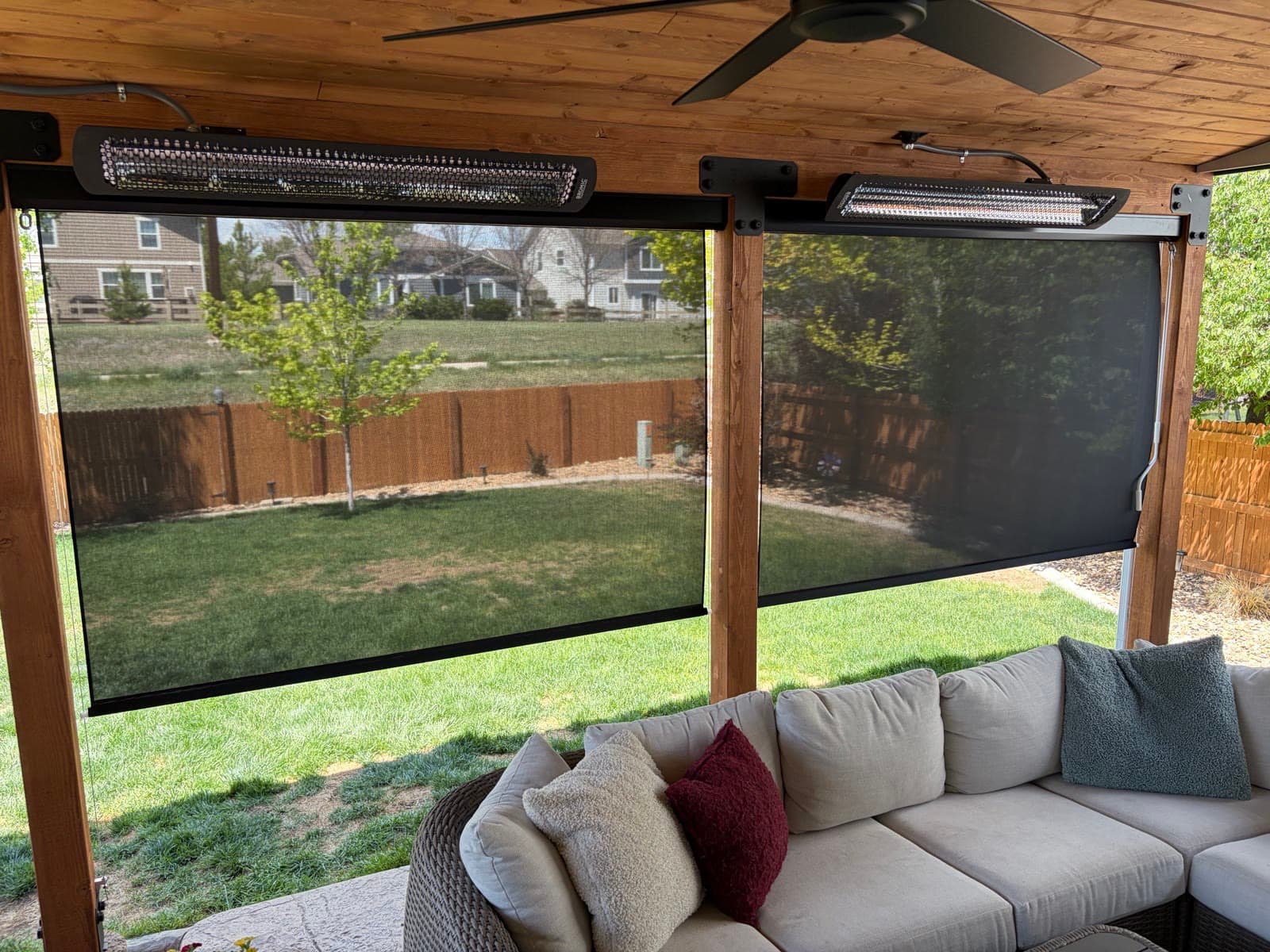 Motorized exterior screens lowered under a cedar pergola with patio heaters