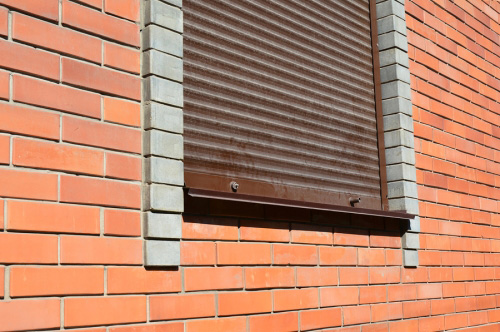 Window with closed shutter on brick wall