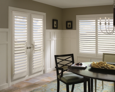 A dining room with white shutters and a table